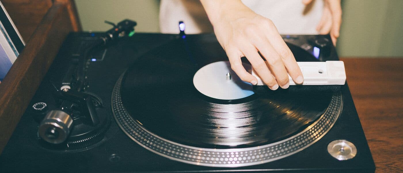 Hand placing the tonearm on a vinyl record on a turntable