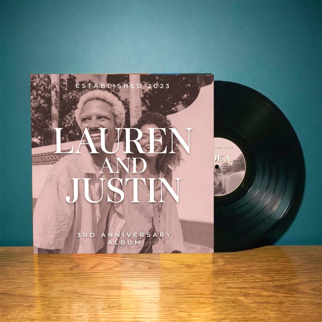 A customer-made custom vinyl record in its sleeve against a teal wall